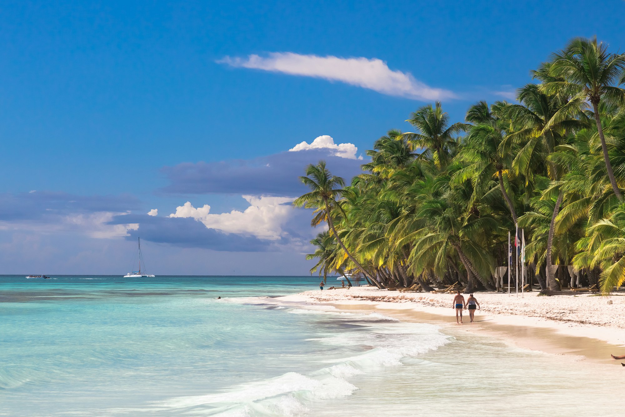 Couple walk on tropical island beach with perfect sunny sky