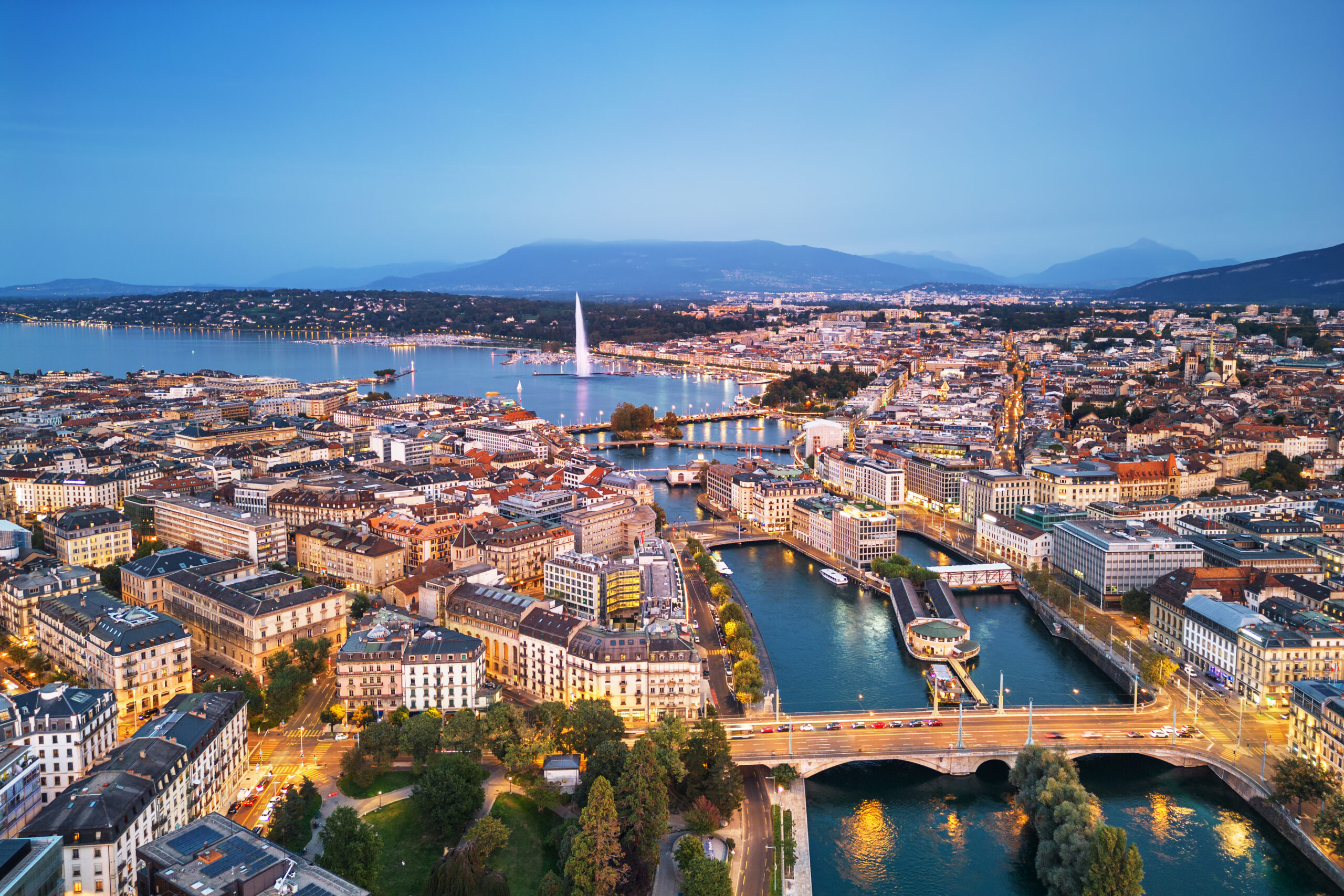 Geneva, Switzerland skyline view towards the Jet d'Eau fountain in Lake Geneva at twilight.